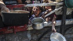 Niños intentan conseguir comida en una cocina comunitaria en Gaza.